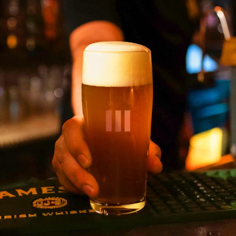 A pint of craft beer with the Mosto logo on the bar